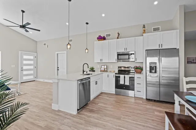 a kitchen with stainless steel appliances granite countertop a refrigerator a stove a sink dishwasher a dining table and chairs with wooden floor
