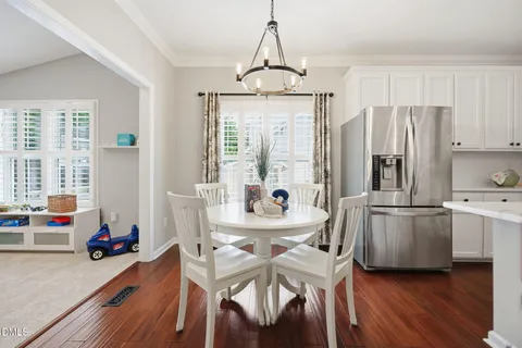 a kitchen with stainless steel appliances a dining table chairs a refrigerator and cabinets