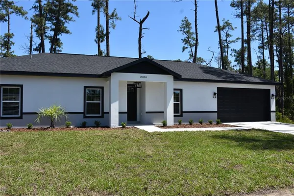 a front view of house with yard and trees in the background