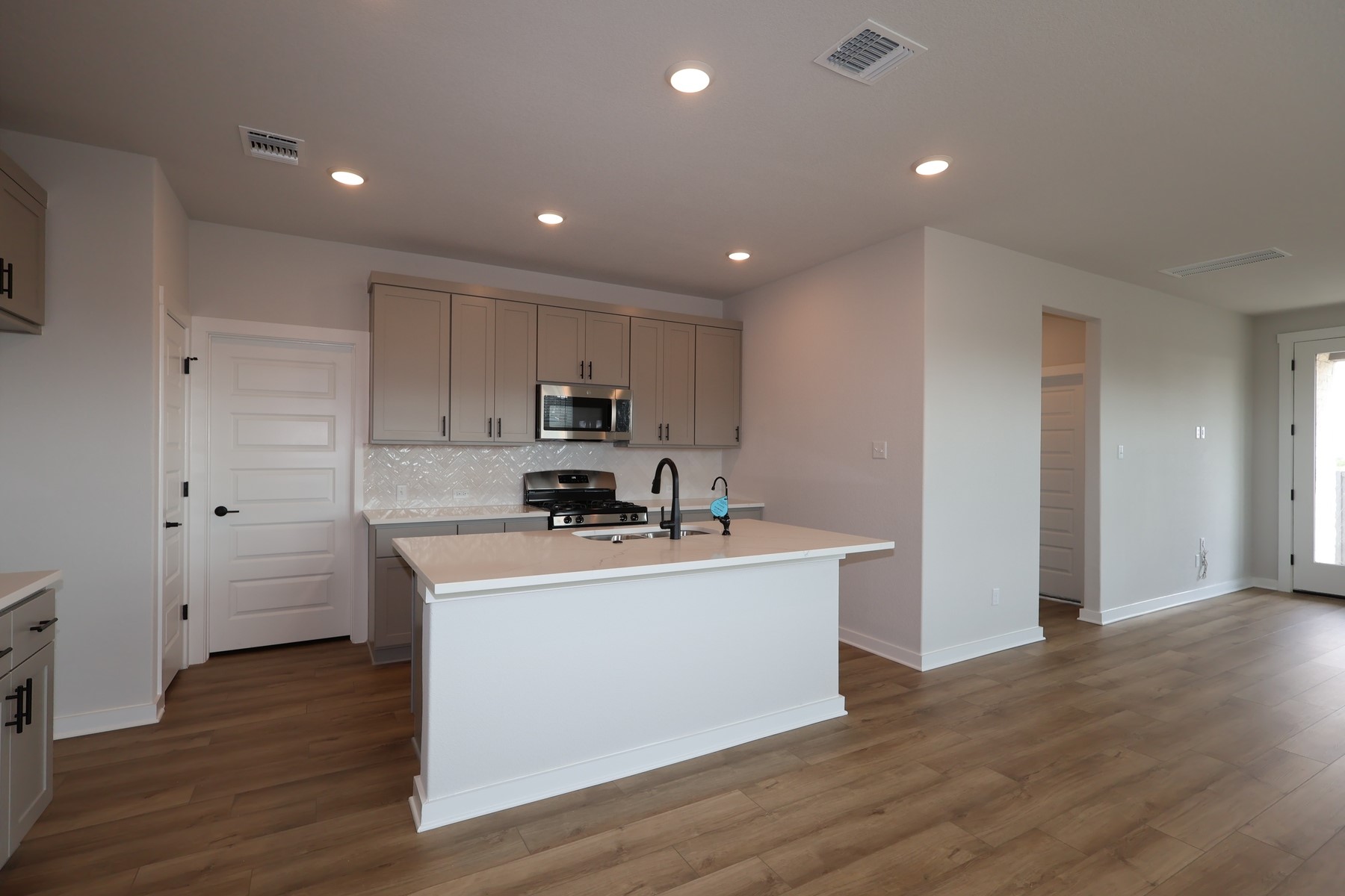 304 Emerie Way Georgetown, TX 78626 - Photo 2 of 15 a view of a kitchen with stainless steel appliances a sink dishwasher a refrigerator and a stove with wooden floor