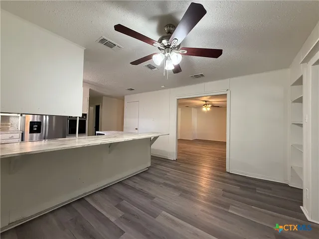 a view of a kitchen with kitchen island wooden floor and a ceiling fan