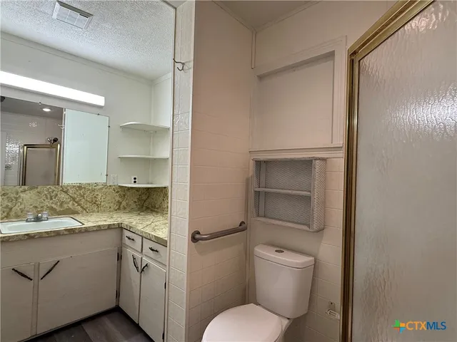 a bathroom with a granite countertop toilet sink and mirror