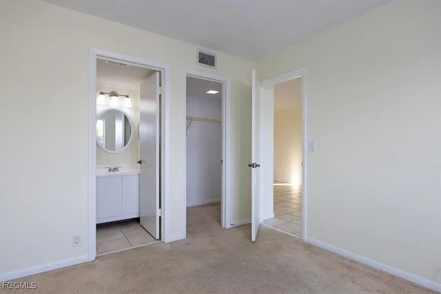 an empty room with mirror and a bathroom
