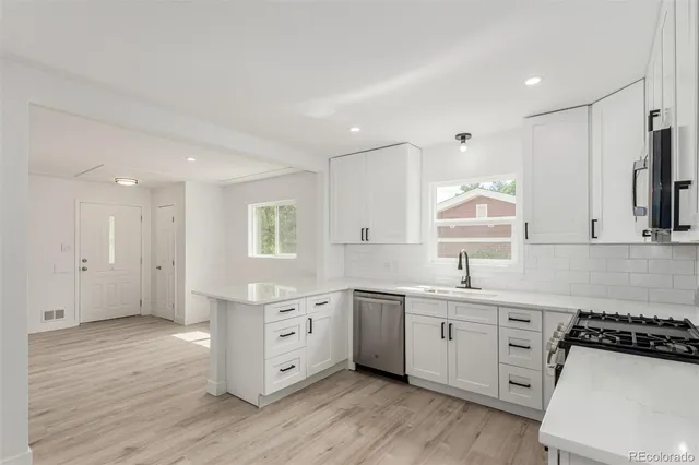 a kitchen with a sink a stove a refrigerator and white cabinets