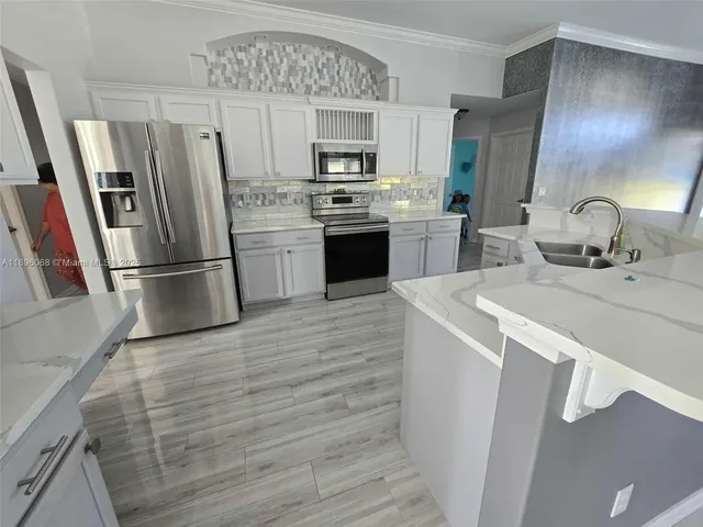 a kitchen with granite countertop a refrigerator stove and sink