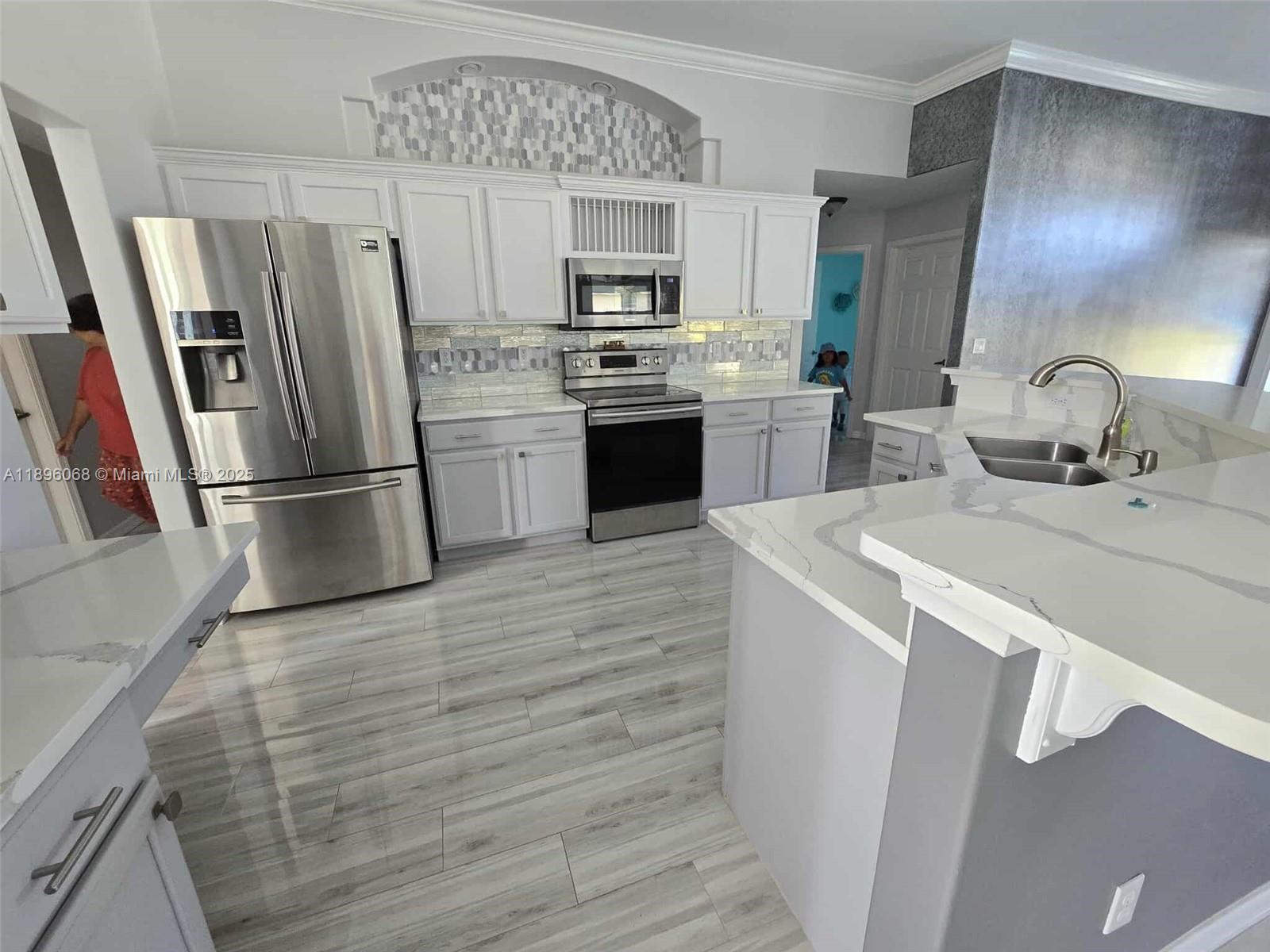 a kitchen with granite countertop a refrigerator stove and sink