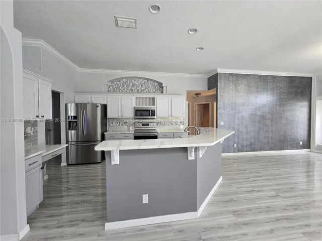 a large kitchen with stainless steel appliances a stove and refrigerator