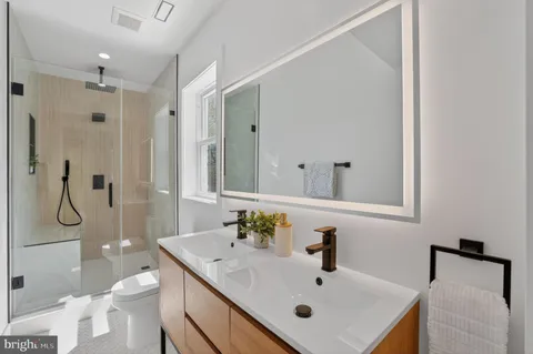 a bathroom with a sink vanity granite toilet and shower