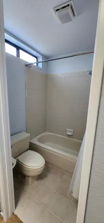 a white toilet sitting next to a bath tub and a shower