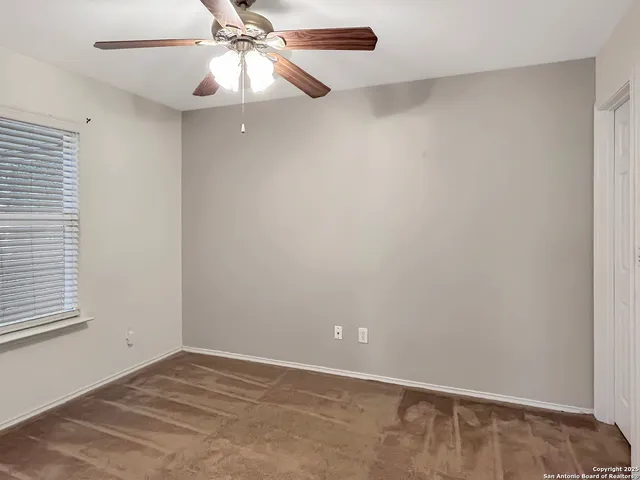 an empty room with a window and a chandelier fan