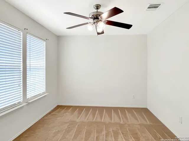 an empty room with a window and a fan