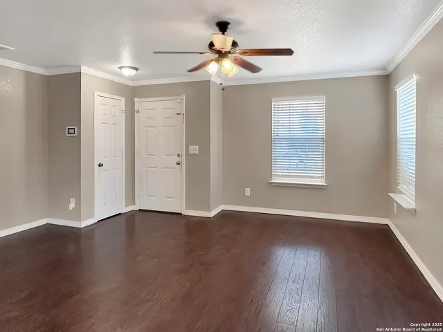 a view of an empty room with wooden floor and a window