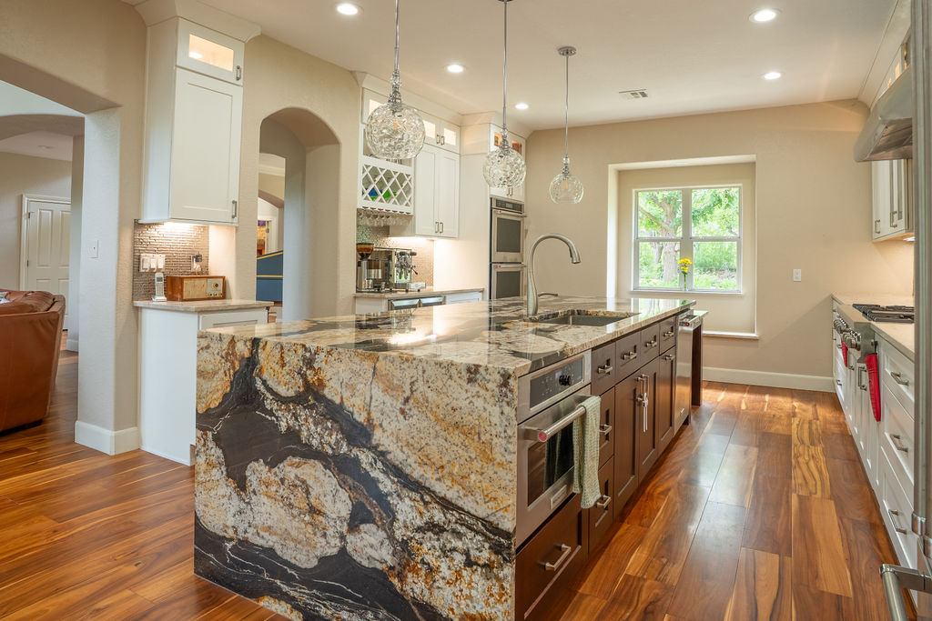 13800 Lone Rider Trail Austin, TX 78738 - Photo 7 of 27 a kitchen with stainless steel appliances kitchen island granite countertop a stove a sink and a refrigerator
