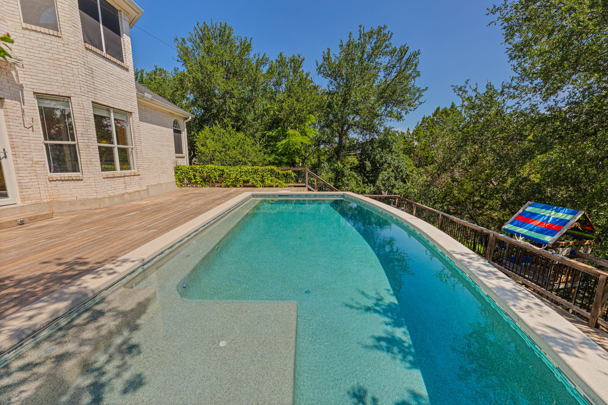 304 River Down Road Georgetown, TX 78628 - Photo 20 of 22 Custom-shaped swimming pool with an integrated sun shelf, surrounded by a wood-finish deck