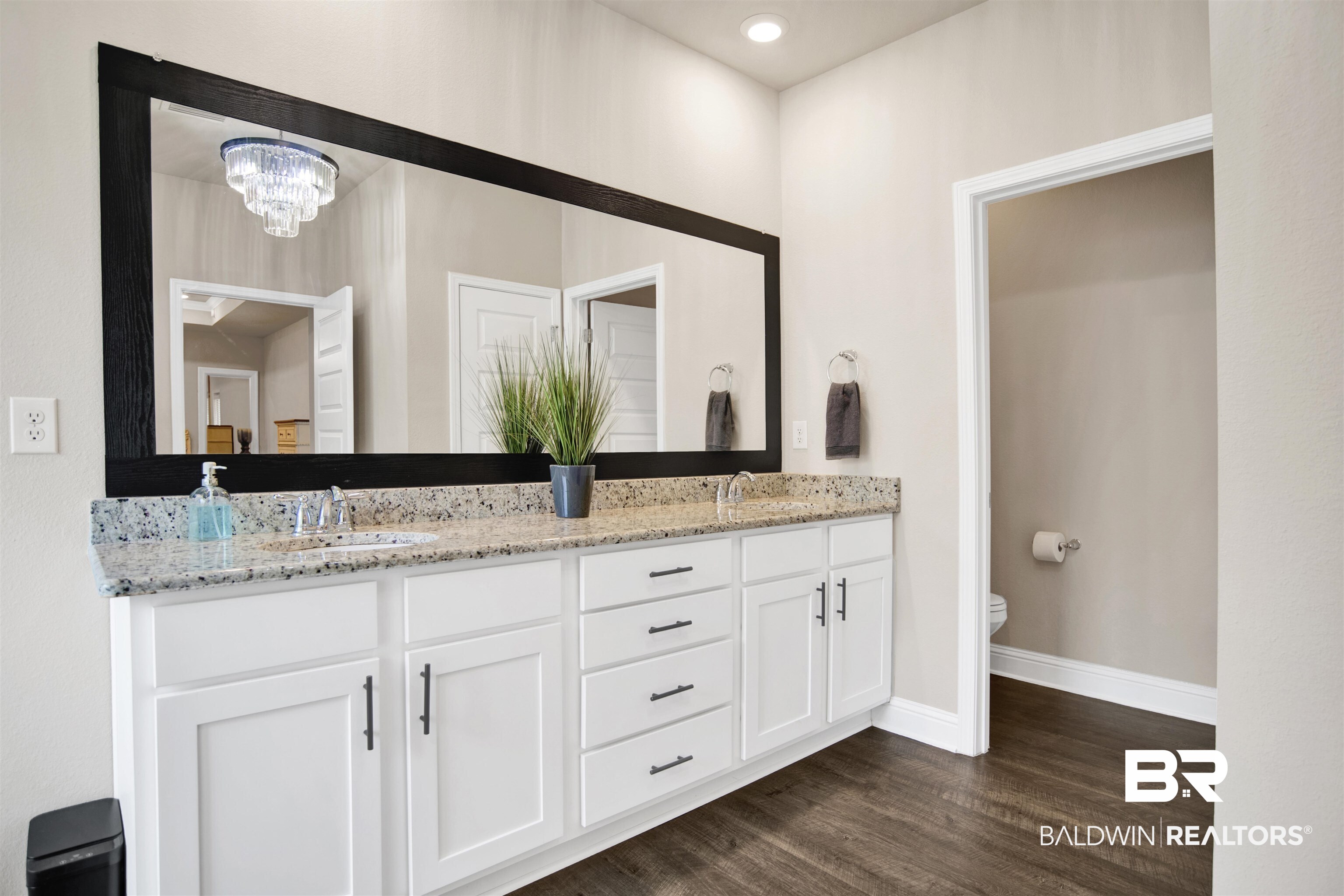 8493 Bronze Lane Foley, AL 36535 - Photo 20 of 38 Double vanity featuring a granite countertop with two undermount sinks, white shaker-style cabinetry, and dark wood-finish flooring