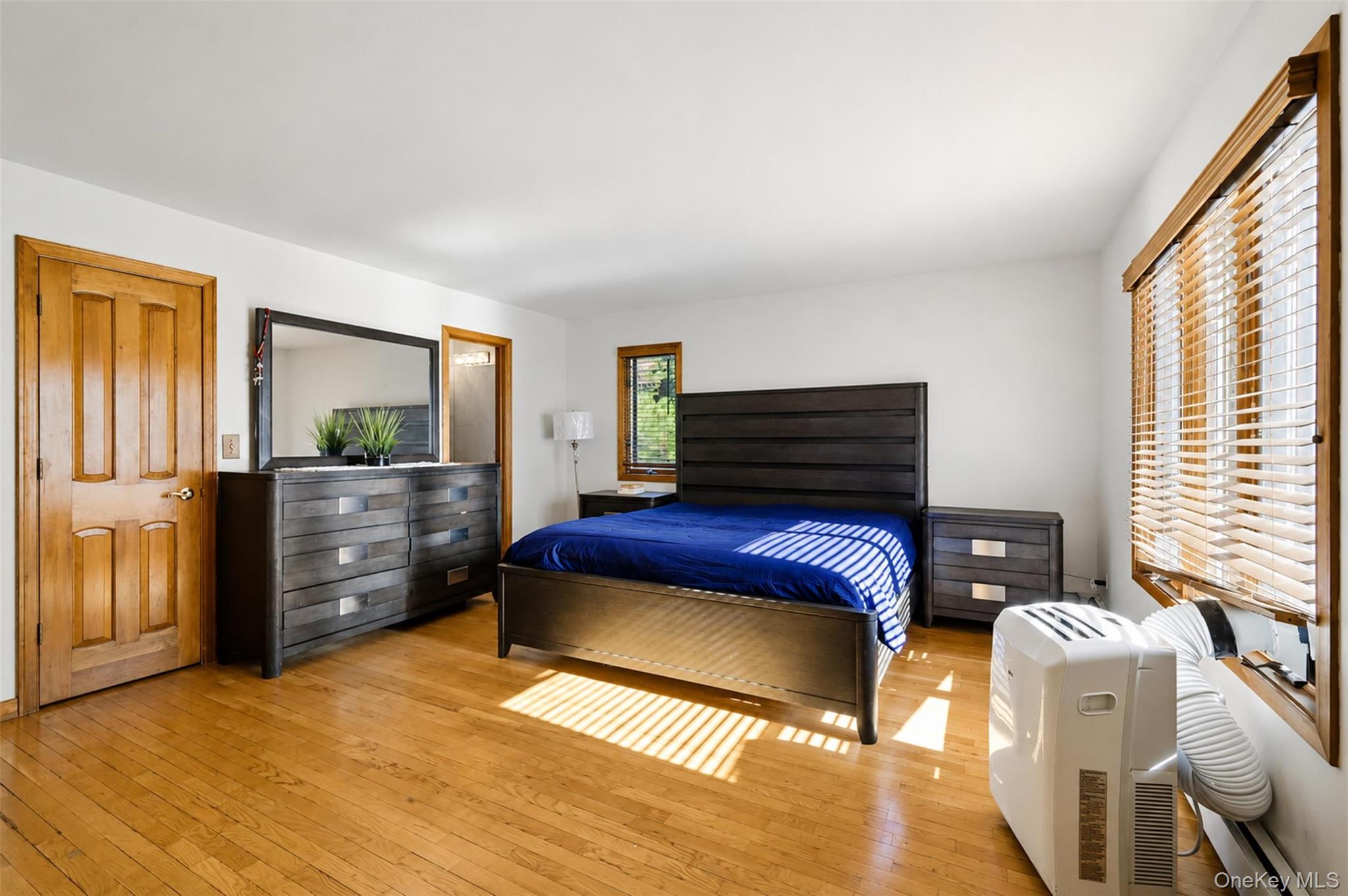 985 Craigville Road Chester, NY 10918 - Photo 17 of 36 Hardwood flooring enhancing a room with white walls, a multi-paneled wood door, and a window featuring wood-slat blinds