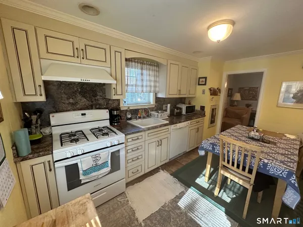 a kitchen with granite countertop a stove a sink dishwasher and cabinets with wooden floor