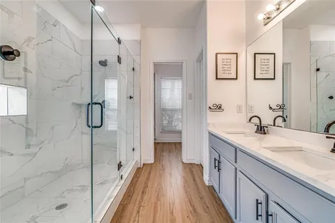a spacious bathroom with a granite countertop sink a mirror and shower