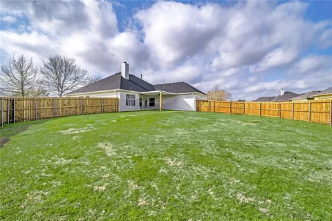 a view of a house with a big yard and large trees