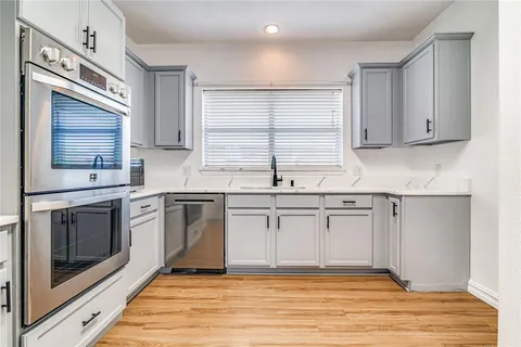 a kitchen with granite countertop white cabinets stainless steel appliances and a sink