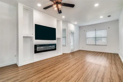 a view of empty room with wooden floor and fan