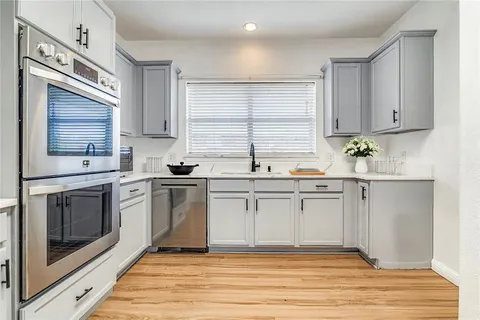 a kitchen with white cabinets appliances and a window