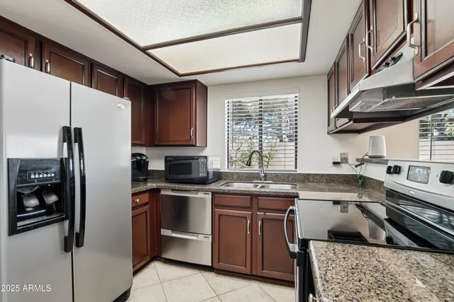 a kitchen with a sink cabinets stainless steel appliances and a window
