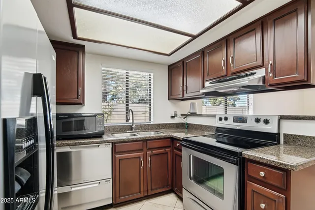 a kitchen with stainless steel appliances granite countertop a sink a stove a microwave and refrigerator