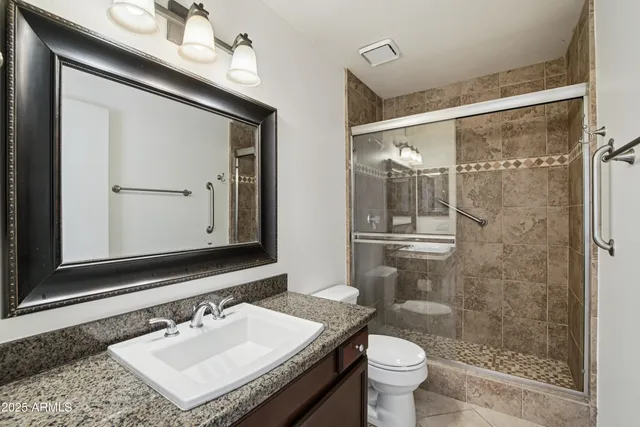 a bathroom with a sink a toilet a mirror and shower