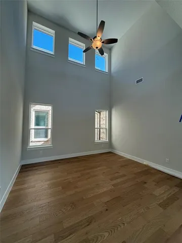 a view of empty room with wooden floor and fan