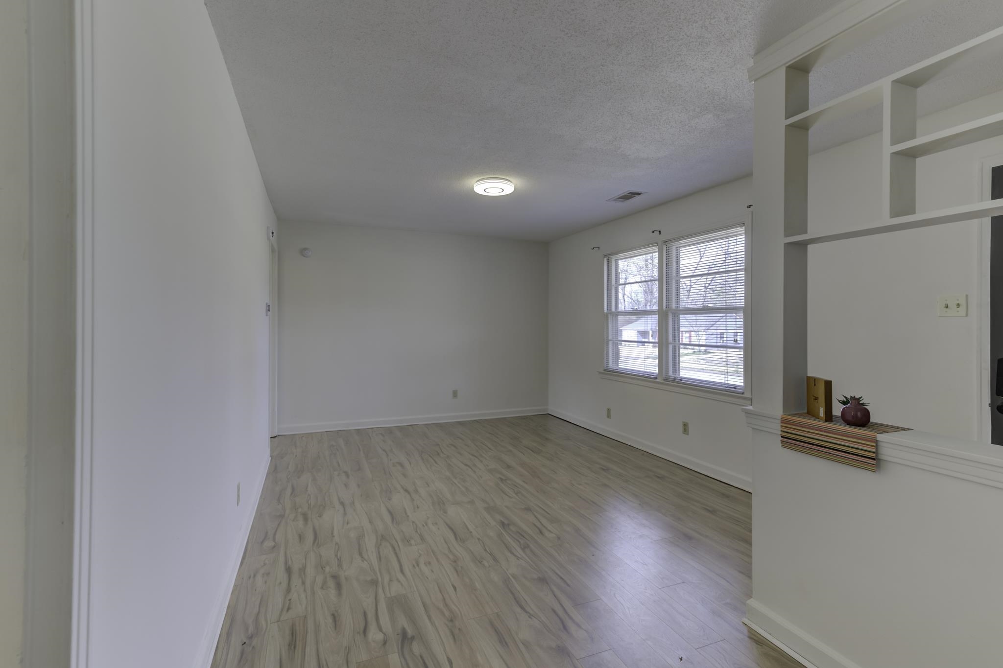 5077 New Castle Road Memphis, TN 38117 - Photo 8 of 37 an empty room with wooden floor and windows
