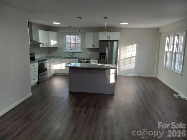 a kitchen with stainless steel appliances wooden floors and view living room