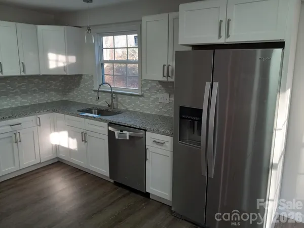 a kitchen with granite countertop stainless steel appliances a refrigerator a sink and cabinets
