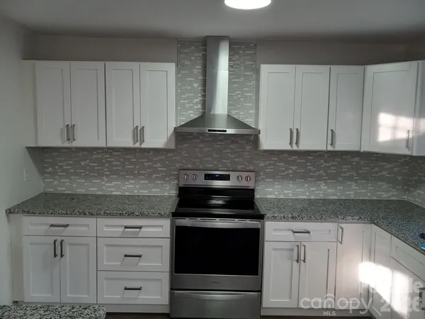 a kitchen with granite countertop white cabinets and black appliances