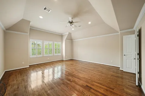 an empty room with wooden floor ceiling fan and windows
