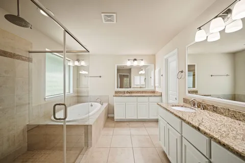 a spacious bathroom with a granite countertop tub sink a mirror and a shower