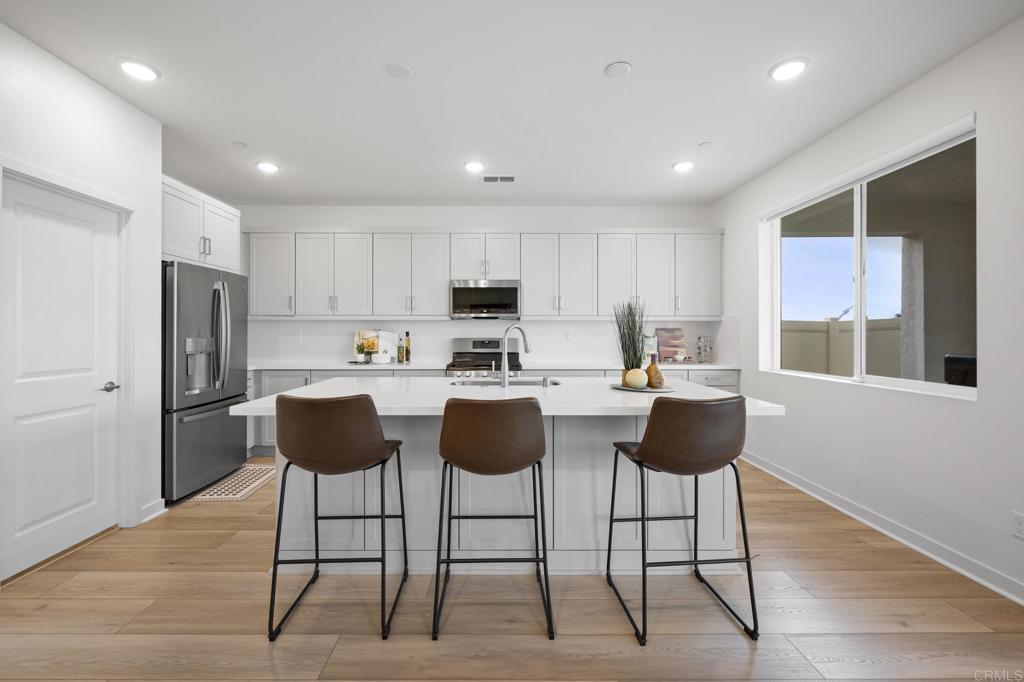 35152 Citrus Lane Fallbrook, CA 92028 - Photo 9 of 34 a kitchen with stainless steel appliances kitchen island granite countertop a refrigerator a stove a sink and white cabinets with wooden floor