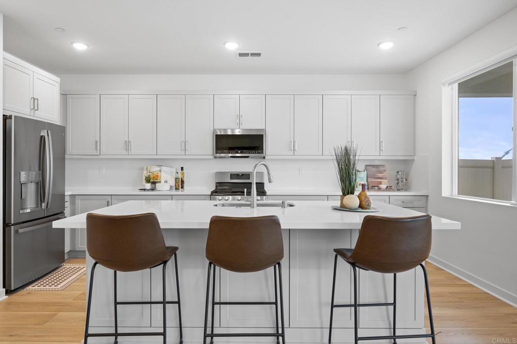35152 Citrus Lane Fallbrook, CA 92028 - Photo 10 of 34 a kitchen with stainless steel appliances granite countertop a stove a refrigerator a dining table and chairs with wooden floor