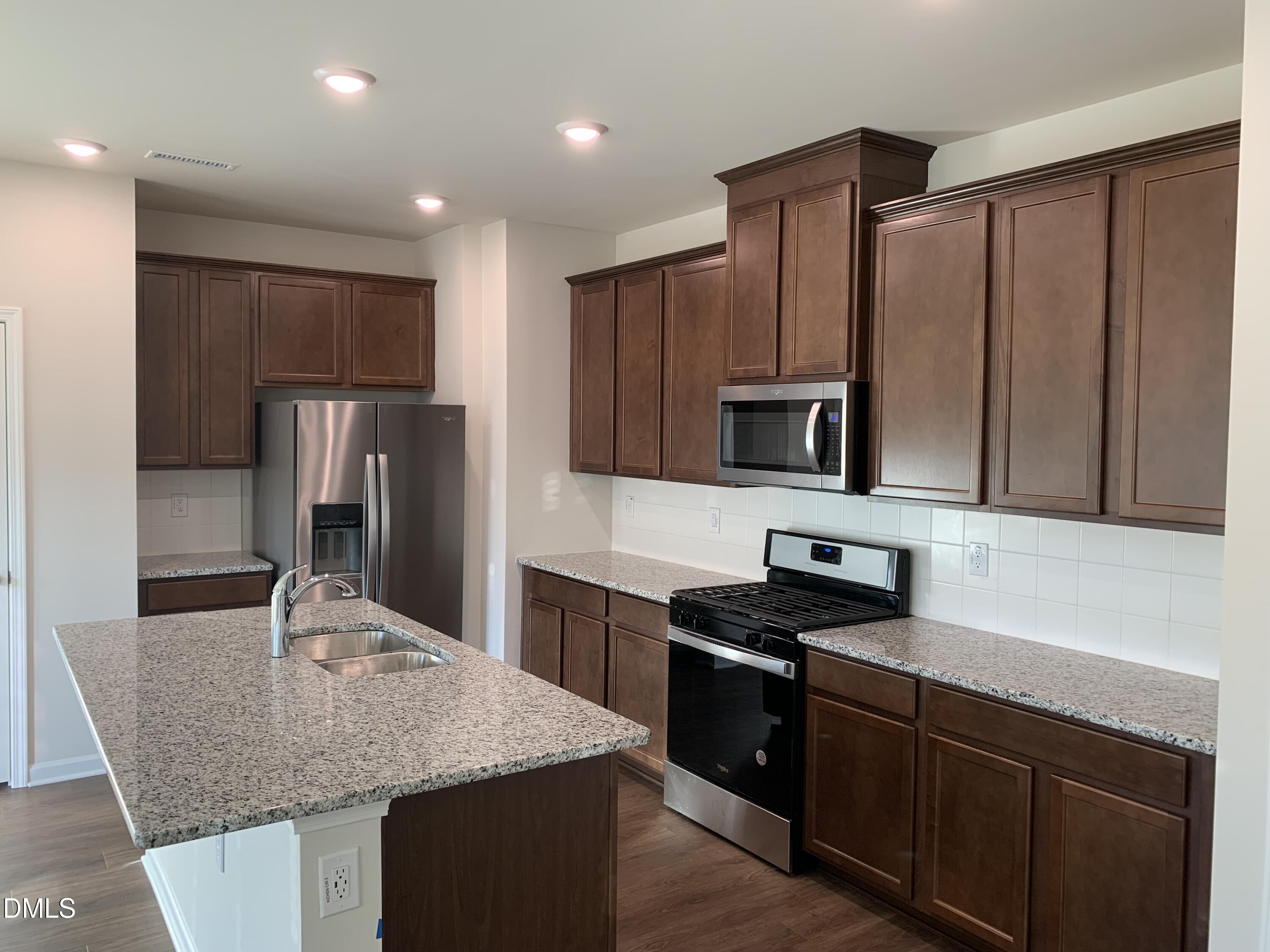 422 Diversity Way Raleigh, NC 27610 - Photo 2 of 10 a kitchen with kitchen island granite countertop stainless steel appliances wooden cabinets a refrigerator and a sink