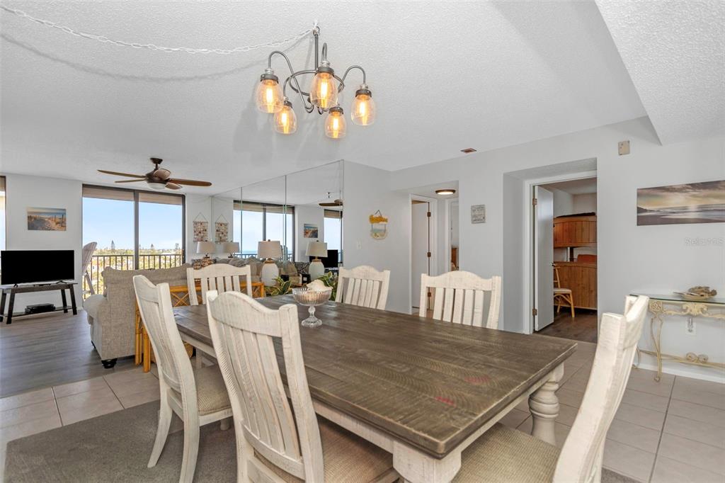 15316 Gulf Boulevard, Unit 604 Madeira Beach, FL 33708 - Photo 24 of 82 a dining room with wooden floor a chandelier a wooden table and chairs