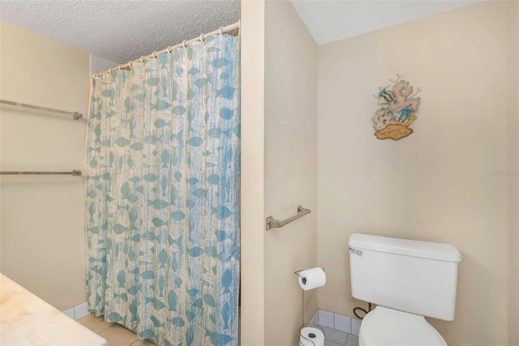 15316 Gulf Boulevard, Unit 604 Madeira Beach, FL 33708 - Photo 33 of 82 a white toilet sitting next to a shower curtain