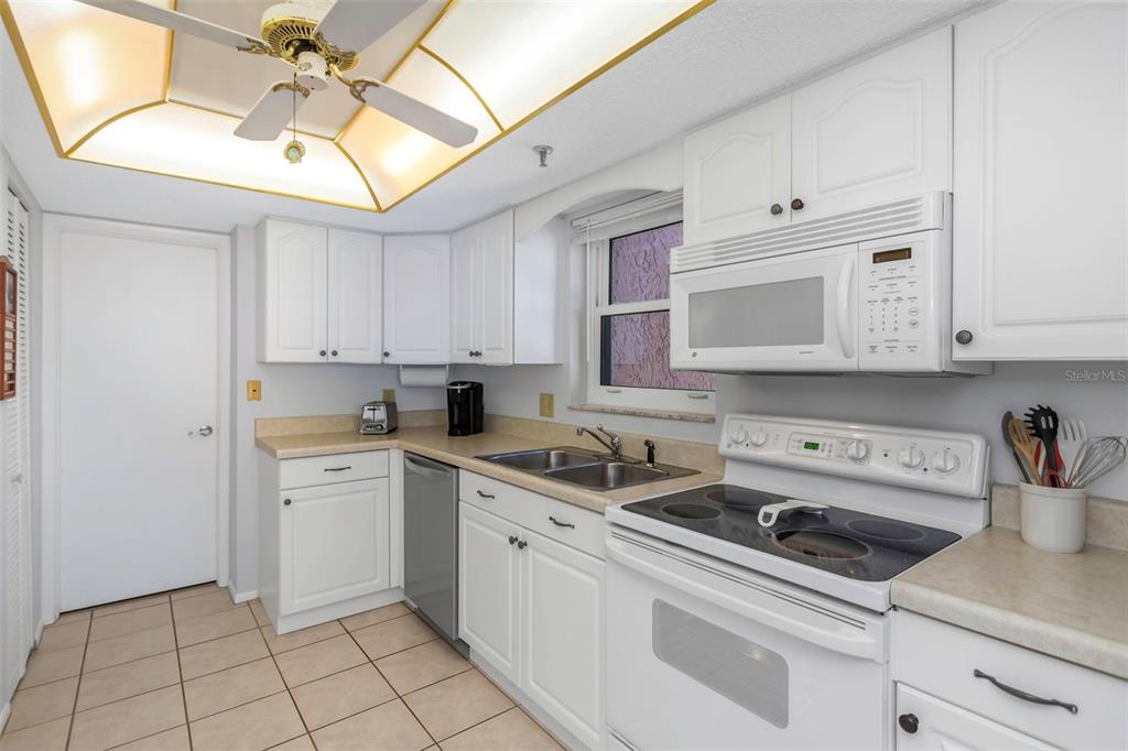 15316 Gulf Boulevard, Unit 604 Madeira Beach, FL 33708 - Photo 6 of 82 a kitchen with white cabinets stainless steel appliances and sink