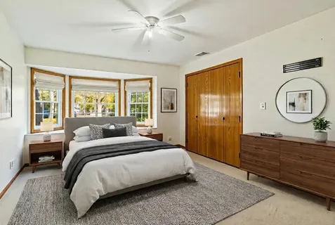 a bedroom with a bed a mirror on the dresser and a window