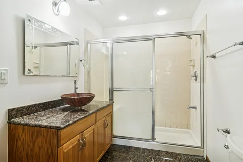 a bathroom with a granite countertop sink mirror and shower