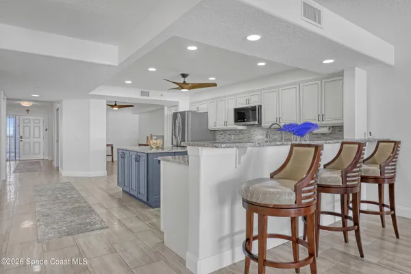 a kitchen with stainless steel appliances kitchen island granite countertop a refrigerator and microwave