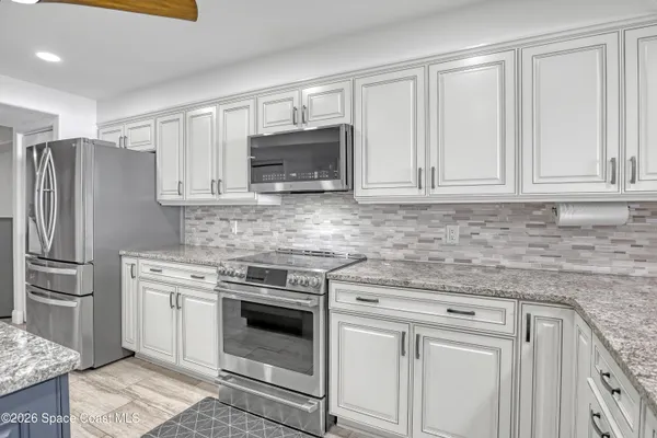 a kitchen with granite countertop white cabinets and stainless steel appliances