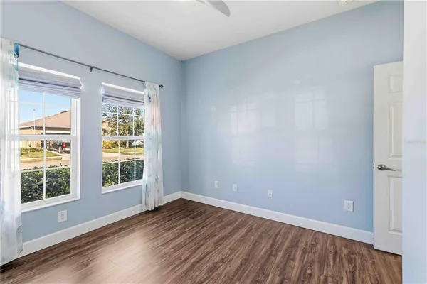 a view of an empty room with wooden floor and a window