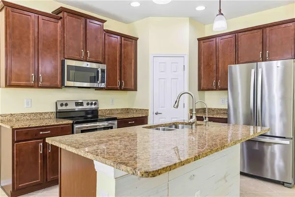 a kitchen with stainless steel appliances granite countertop a refrigerator a stove a sink and a microwave