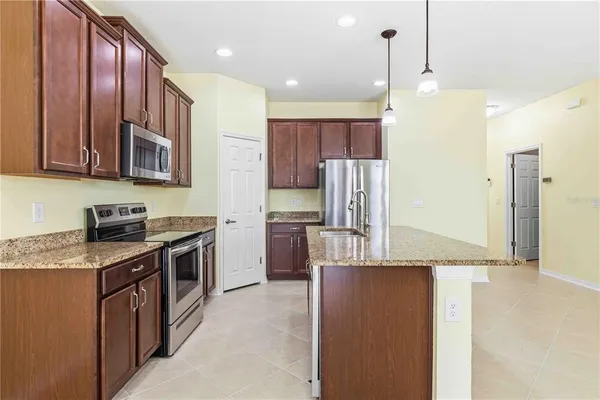 a kitchen with stainless steel appliances granite countertop a refrigerator a stove and a sink