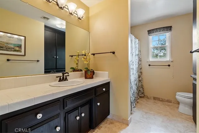 a bedroom with a bed a chandelier and a dresser